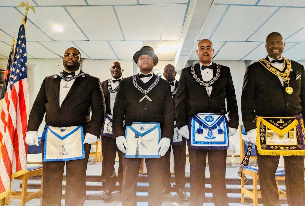 A group of men in suits and ties holding their masonic regalia.