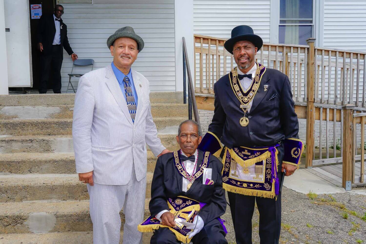 Three men in suits and hats standing on steps.