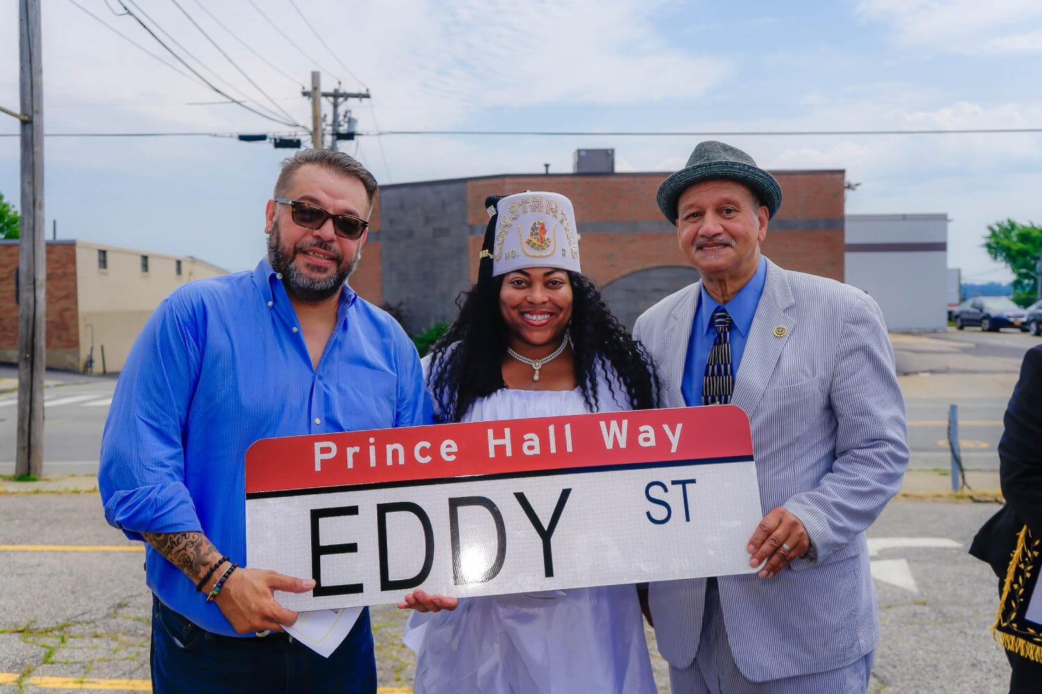 Three people holding a sign that says " prince hall way eddy st ".