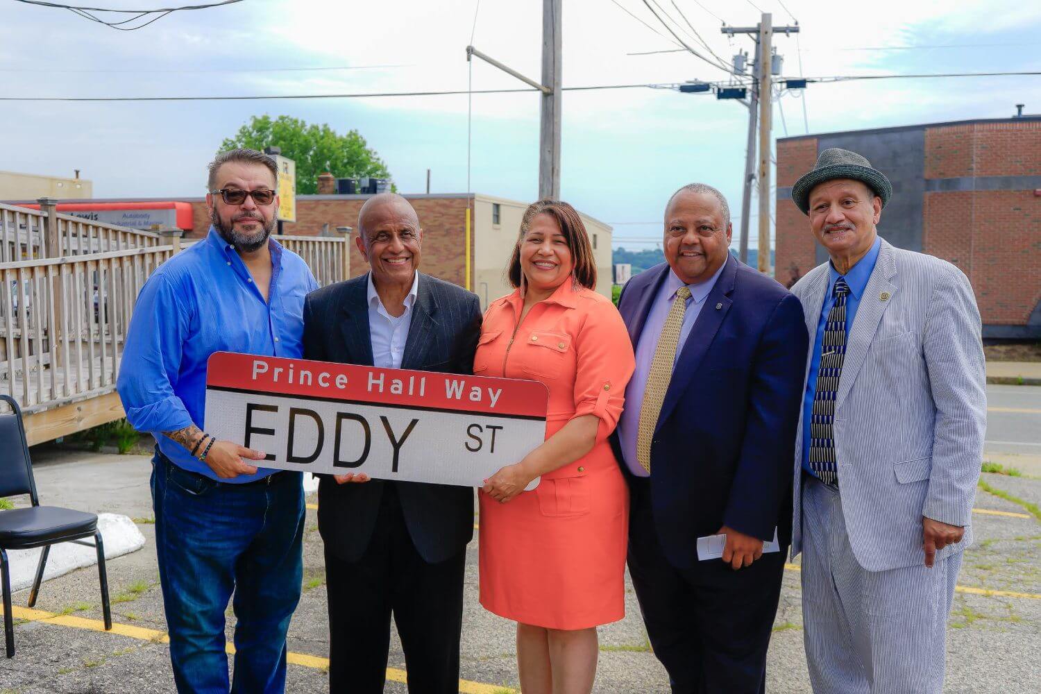 A group of people standing next to each other holding up a street sign.